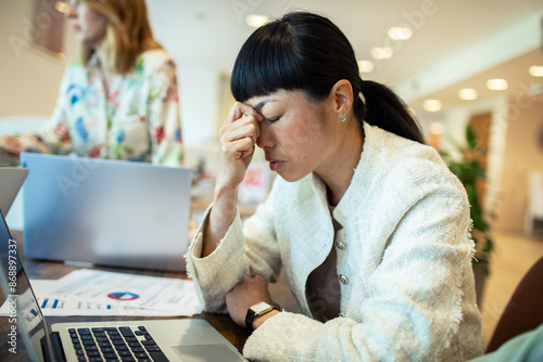 Frustrated Businesswoman with Headache Working on Laptop in Office
