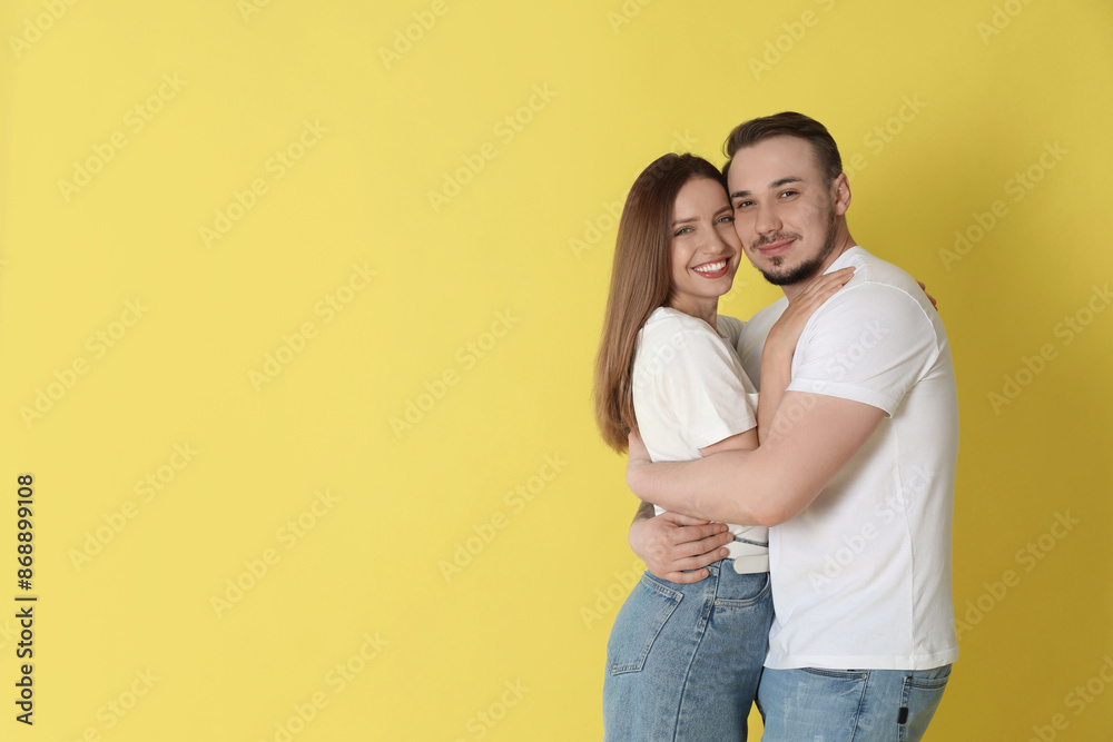 Fototapeta premium Happy couple hugging on yellow background. Space for text