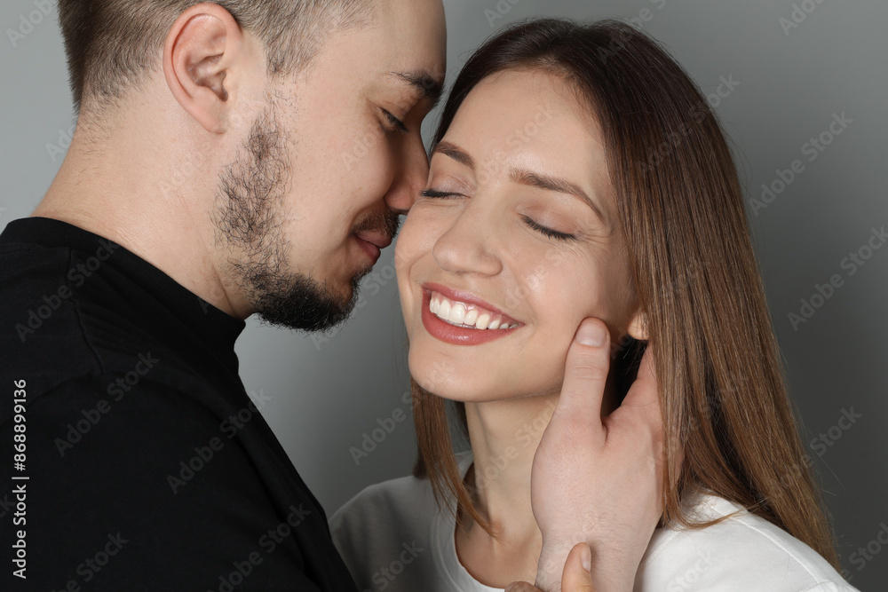 Man hugging and kissing his happy girlfriend on grey background Man hugging and kissing his happy girlfriend on grey background