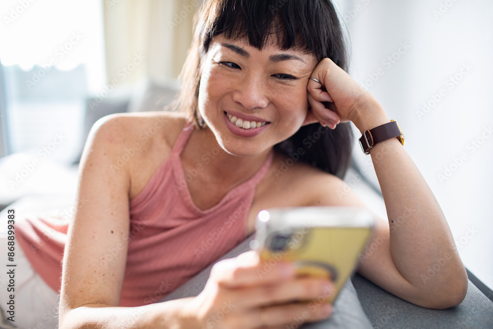 Smiling Asian woman using smartphone at home Smiling Asian woman using smartphone at home