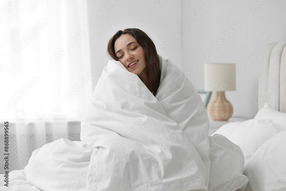 Happy woman wrapping in blanket sitting on bed. Good morning Happy woman wrapping in blanket sitting on bed. Good morning