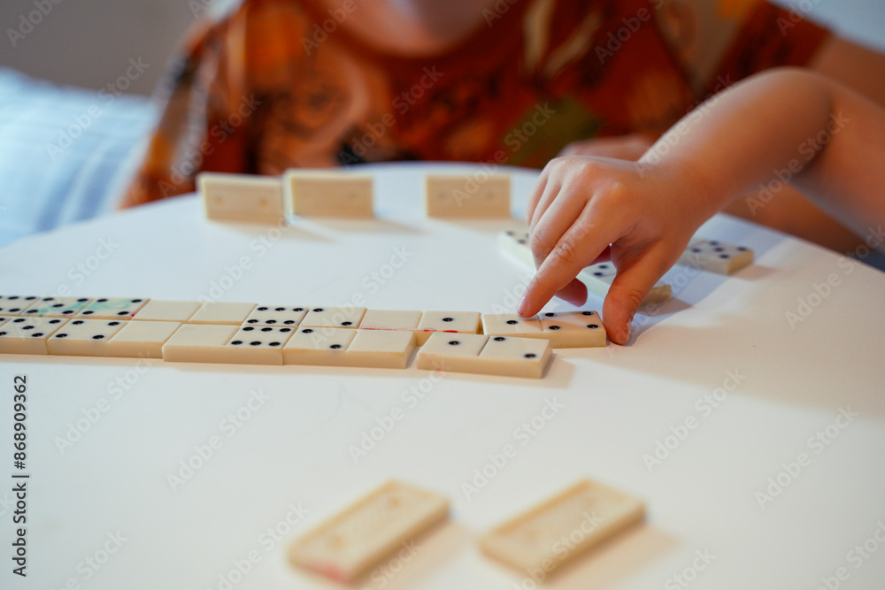 Closeup shot of kid putting domino tile on the table 