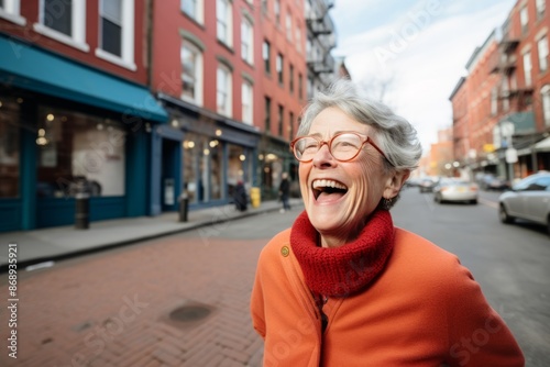 Portrait of a happy senior woman in red sweater and glasses on a city street