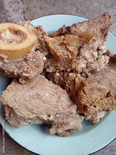 Beef that has been cooked after being boiled is placed on a plate on the cement floor. Close up food. photo