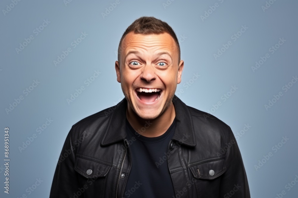 Man with leather jacket and surprised facial expression over blue studio background. Man with leather jacket and surprised facial expression over blue studio background.
