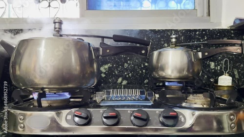 two pressure cooker on the gas top, one Pressure cooker is whistling as Rice is being cooked.