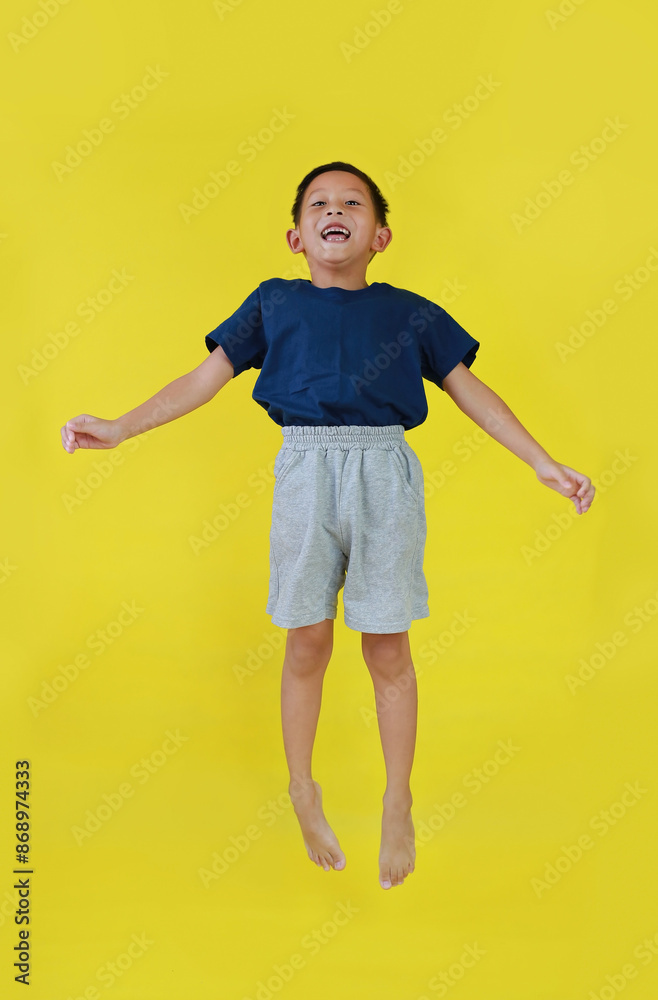 Cheerful Asian little boy kid jumping in air over yellow studio background. Cheerful Asian little boy kid jumping in air over yellow studio background.