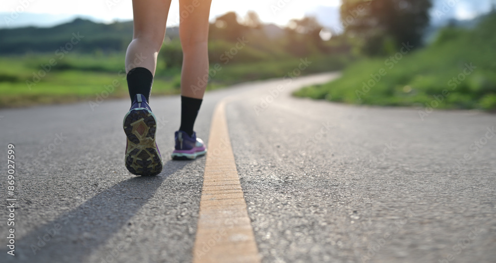 From the rear view, the focus is on the sneakers of an exerciser walking along the road.. From the rear view, the focus is on the sneakers of an exerciser walking along the road..