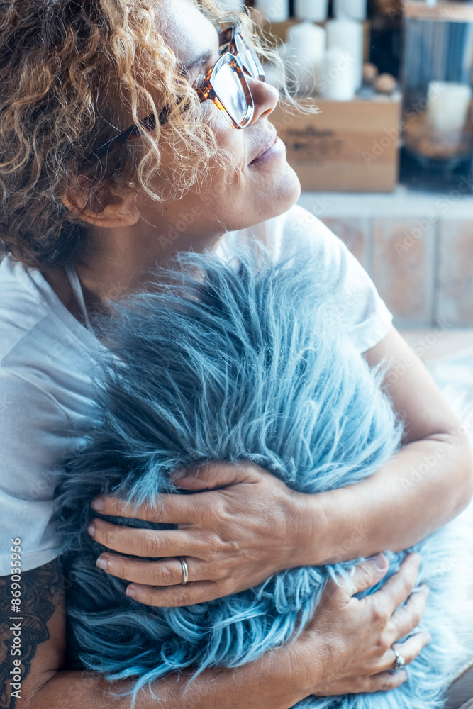 Fototapeta premium One woman embracing pillow at home looking outside the window. Love emotion concept and daydreaming femalepeople in indoor leisure activity alone