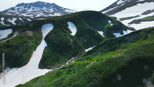 Small valley of geysers in Kamchatka, Russia. Green mountains and volcanoes with snow. Aerial drone view. Beautiful summer landscape. 
 photo