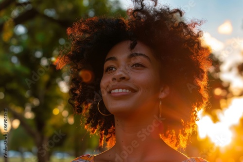 beautiful african american woman smiling and looking away at park during sunset © senyumanmu