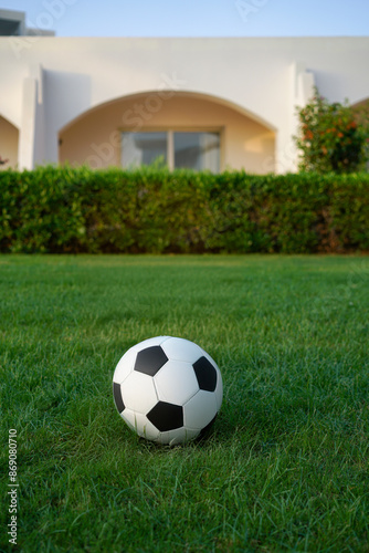 The girl on the grass in a swimsuit practices yoga on a towel against the bungalow