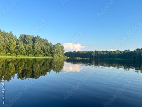 beautiful lake on the shore forest with reflection in water blue sky in reflection of water.