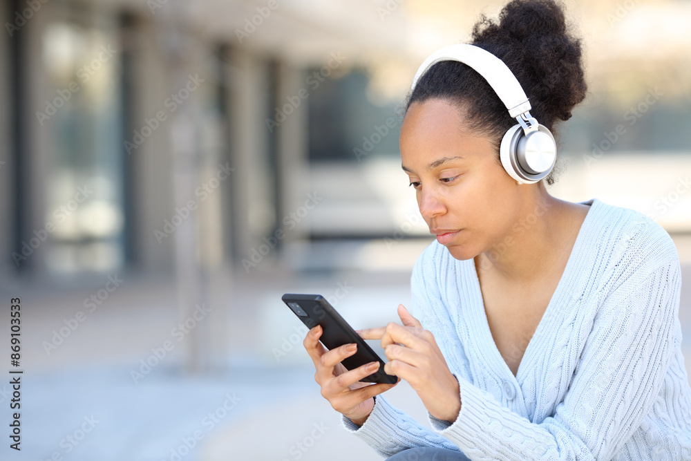 Black woman wearing headphone checking phone Black woman wearing headphone checking phone