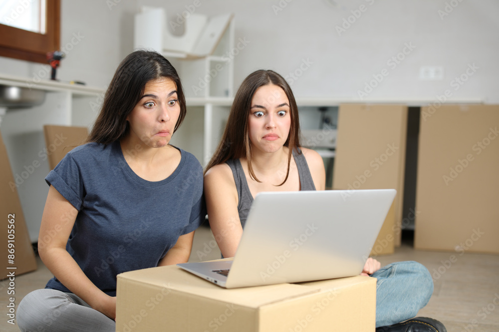 Perplexed roommates checking laptop moving house Perplexed roommates checking laptop moving house
