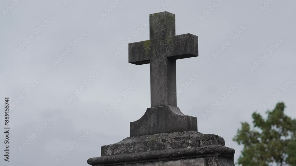 A Weathered Stone Cross in a cemetery symbolizes Christian heritage and spirituality A Weathered Stone Cross in a cemetery symbolizes Christian heritage and spirituality