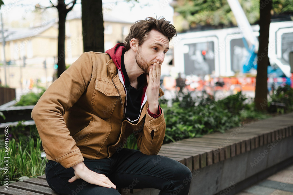 Thoughtful man with hand covering mouth sitting on bench Thoughtful man with hand covering mouth sitting on bench