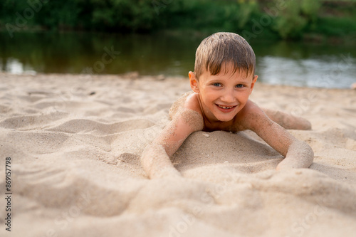 Smiling boy lying on sand at beach photo