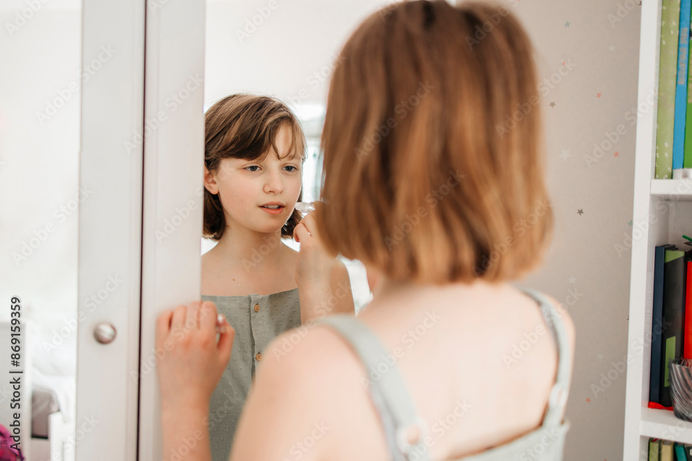 Girl standing in front of mirror and applying hygienic lipstick at home Girl standing in front of mirror and applying hygienic lipstick at home