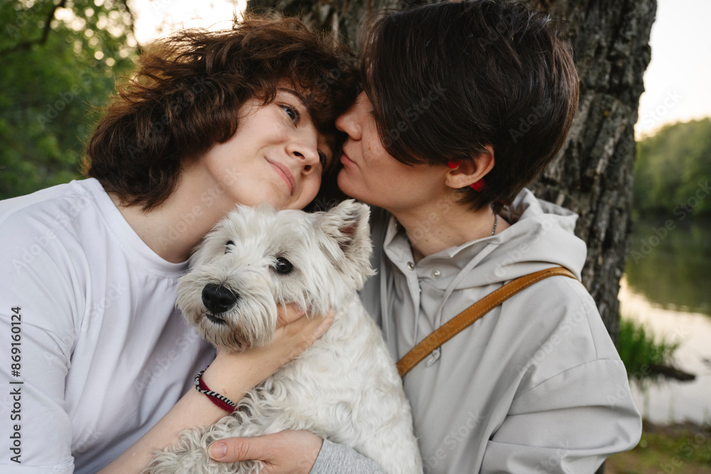 Mother kissing daughter standing with dog at park Mother kissing daughter standing with dog at park