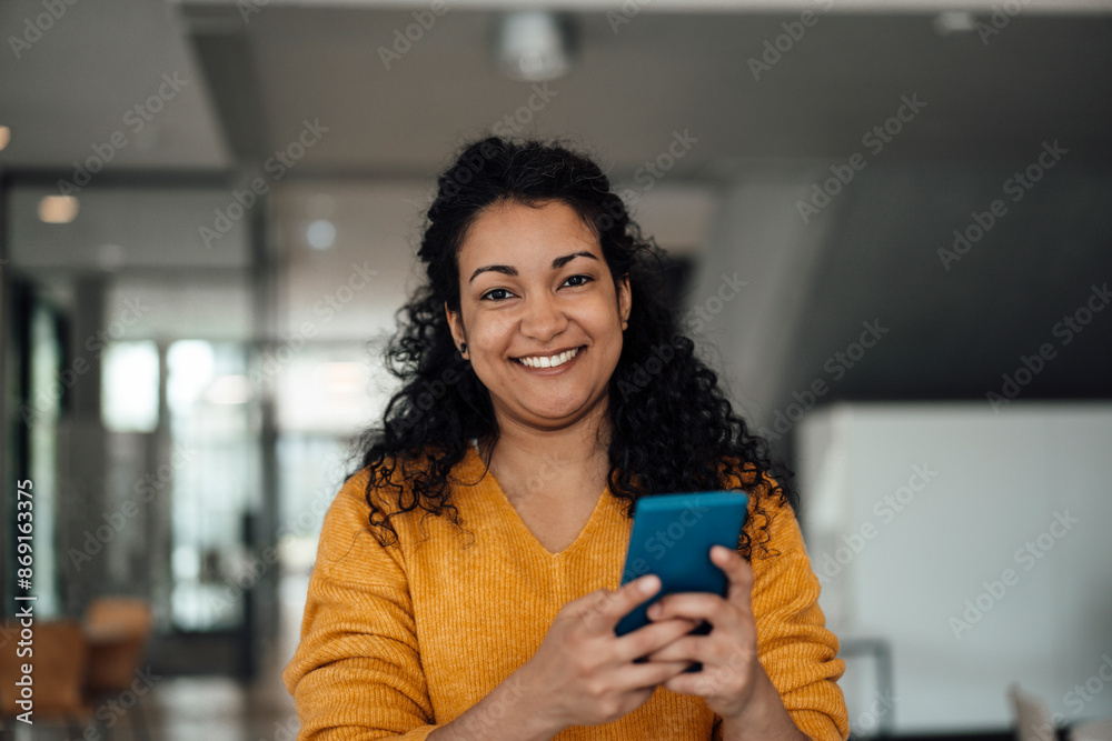 © Westend61 - Happy businesswoman holding smart phone at office