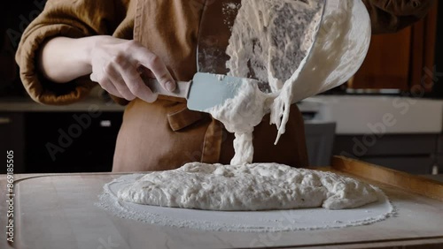 woman carefully transfers the dough from the glass bowl photo