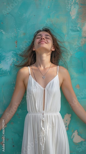 A young woman wearing a white dress leaning against the wall