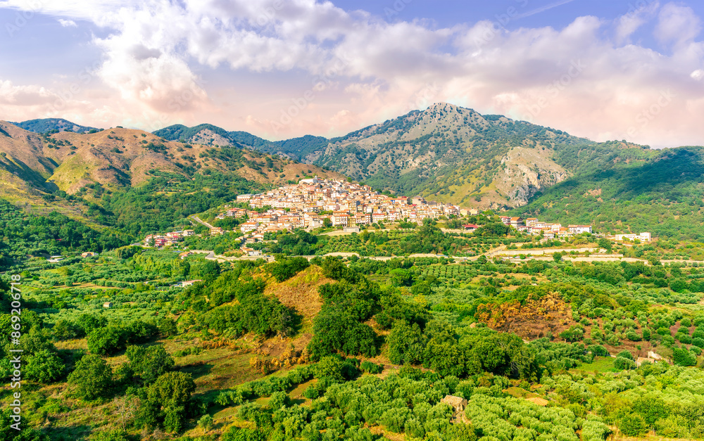 Obraz premium amazing mountain landscape with old yellow italian town among green beatiful mountains and cloudy sky above