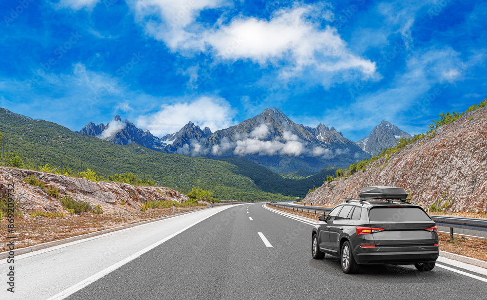 Travel car drives along the highway against the backdrop of rocky mountains on a sunny day. Travel car drives along the highway against the backdrop of rocky mountains on a sunny day.