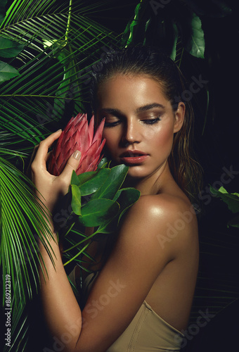 A beautiful tanned girl with natural make-up and wet hair stands in the jungle among exotic plants.fashion, beauty, health, ecology, makeup, personal care, hair, nature.