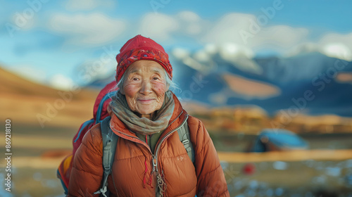 An aged Asian woman with a wrinkled face and a radiant smile, in a climbing suit, standing on top of a mountain, majestic mountain landscapes stretch around.