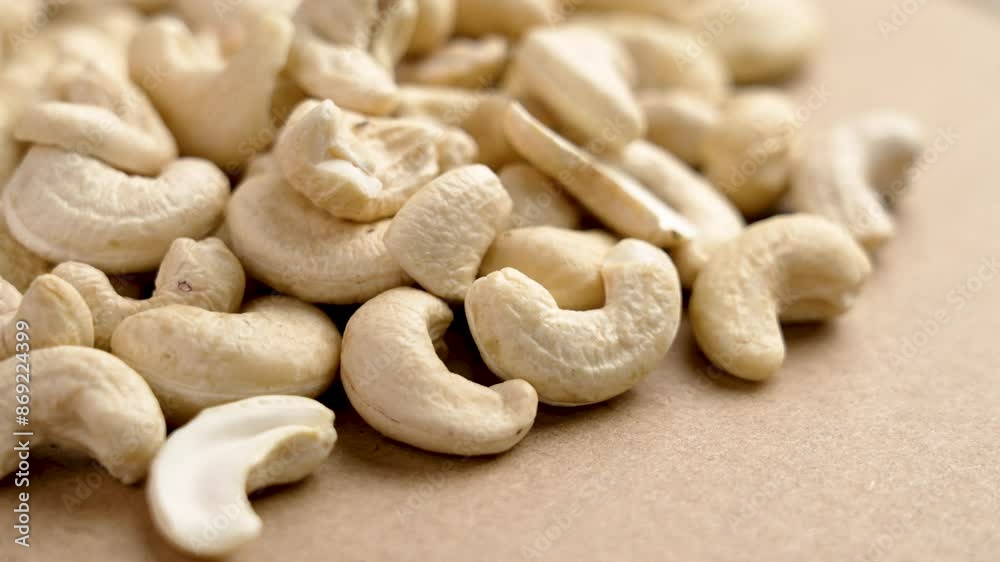 Group of raw cashew nuts with creamy color and natural texture on a brown background close up. Rotation Group of raw cashew nuts with creamy color and natural texture on a brown background close up. Rotation