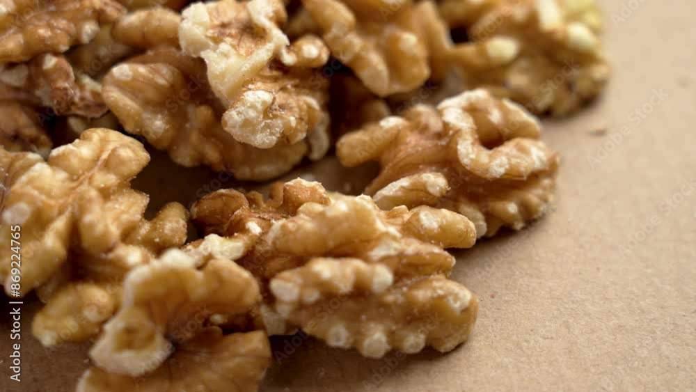 Walnut halves scattered on a brown paper surface close up. Raw healthy ingredient. Rotation Walnut halves scattered on a brown paper surface close up. Raw healthy ingredient. Rotation