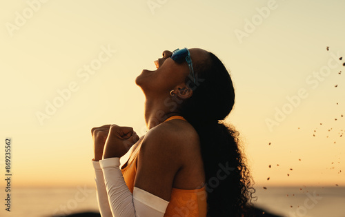 Young woman celebrating victory on the beach volleyball court at sunset photo