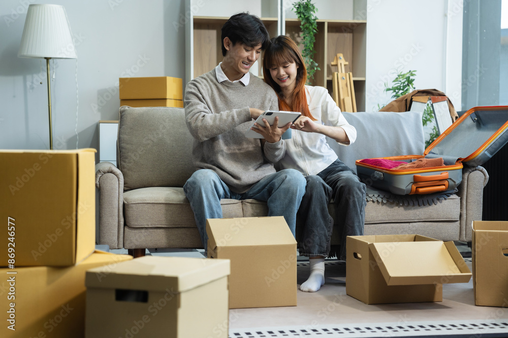 Young couple relaxing sitting on the floor around cardboard boxes at home, smiling happy moving to a new house.