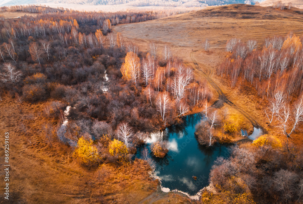 River in the autumn forest at sunset. Dirty road across the pond. Aerial view.