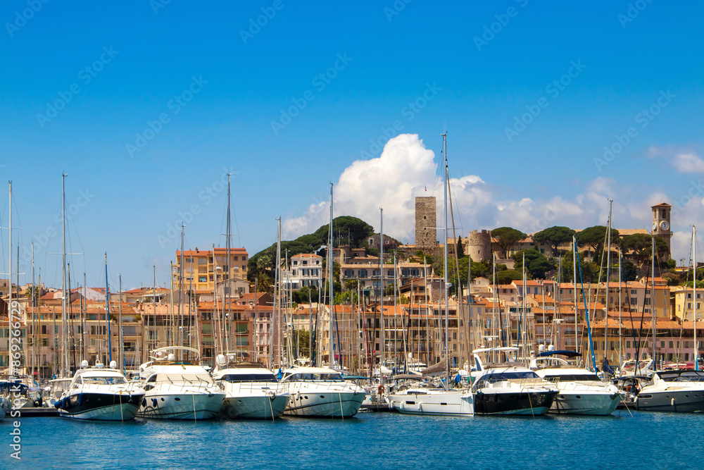 Luxury yachts, modern buildings, and sailboats in a beautiful Mediterranean marina view. Old city and harbor in Cannes, French Riviera, France.
