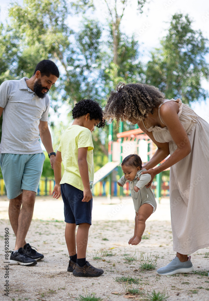 Latin family in a playground with their two children. Family of father, mother, child and baby Latin family in a playground with their two children. Family of father, mother, child and baby