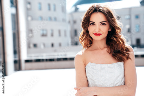 Free Download Young beautiful serious brunette female in trendy evening silver dress. Sexy carefree woman posing in the street at sunny day. Fashionable model with evening bright makeup and red lips, outdoors - GFXLoad