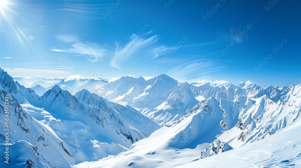 A panoramic view of a snow-capped mountain range with a bright blue sky and sun shining. A panoramic view of a snow-capped mountain range with a bright blue sky and sun shining.
