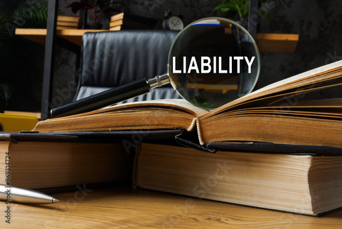 Legal liability concept. Law books and magnifying glass. photo