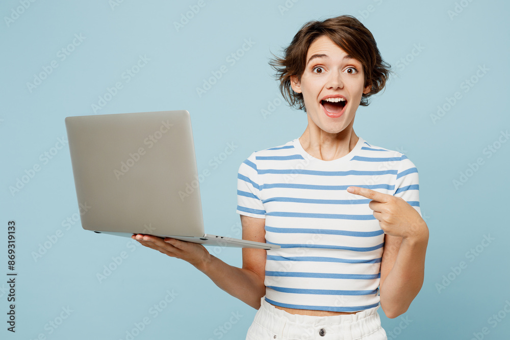 © ViDi Studio - Young happy IT woman wears striped t-shirt casual clothes hold use work point index finger on laptop pc computer isolated on plain pastel light blue cyan background studio portrait. Lifestyle concept. © ViDi Studio - Young happy IT woman wears striped t-shirt casual clothes hold use work point index finger on laptop pc computer isolated on plain pastel light blue cyan background studio portrait. Lifestyle concept.