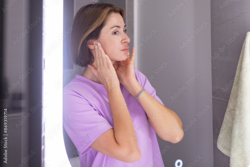 Young beautiful woman looking at mirror and confusing because of new wrinkles Young beautiful woman looking at mirror and confusing because of new wrinkles