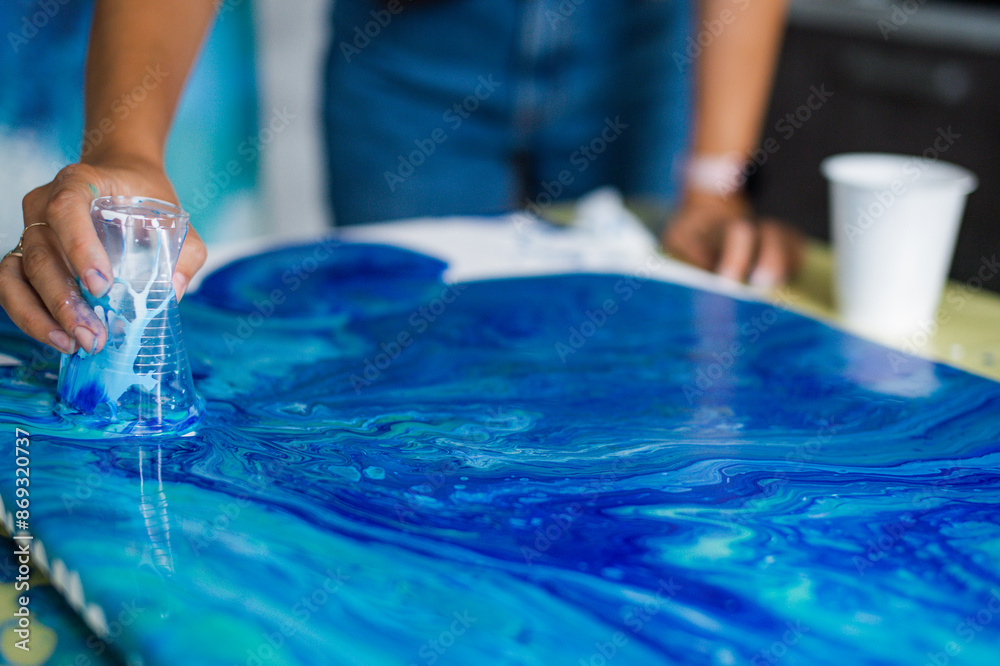 Fototapeta premium Person creating blue acrylic pour art on canvas. Art and creativity concept.