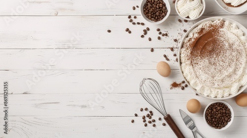 A top-down view of a white wooden table with a bowl of whipped cream, a small cake, a bowl of coffee beans, and a small spoon