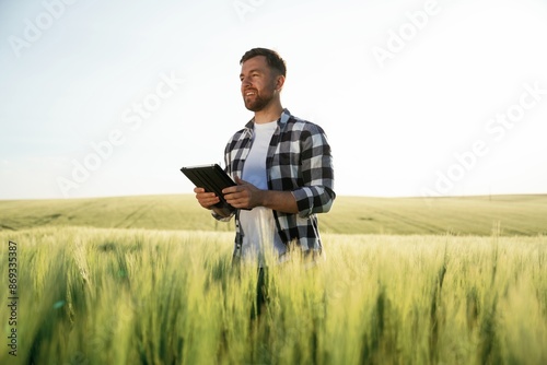 Digital tablet in hands. Handsome man is on the agricultural field at daytime © standret
