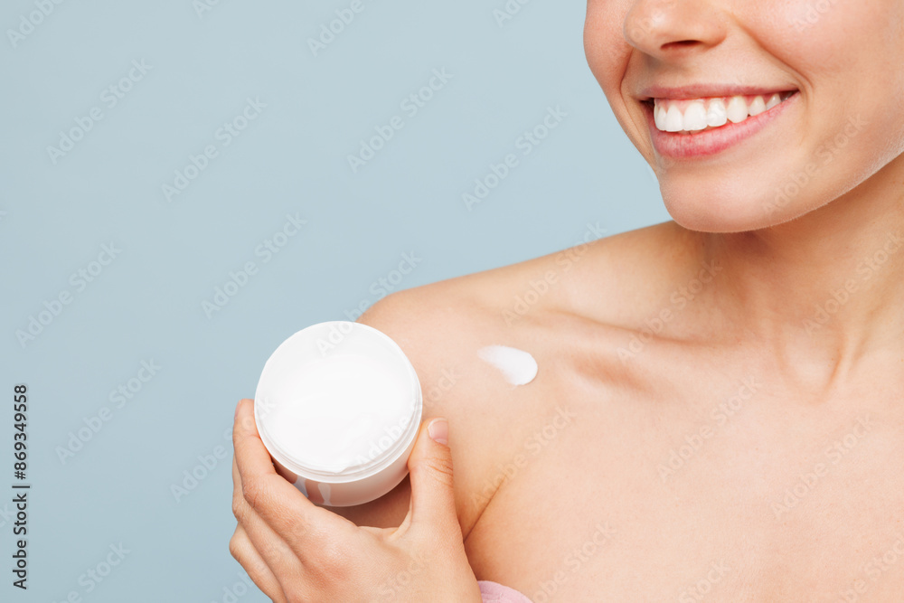 Close up cropped fun half naked topless young woman with nude make up apply moisturizer, body cream from container isolated on plain blue background. Skin care healthcare cosmetic procedures concept. Close up cropped fun half naked topless young woman with nude make up apply moisturizer, body cream from container isolated on plain blue background. Skin care healthcare cosmetic procedures concept.