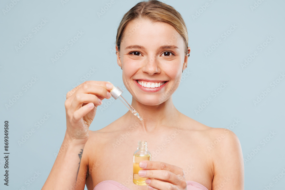 Beautiful smiling fun half naked topless young woman with nude make up apply face body oil, moisturizing serum isolated on plain blue color background Skin care healthcare cosmetic procedures concept Beautiful smiling fun half naked topless young woman with nude make up apply face body oil, moisturizing serum isolated on plain blue color background Skin care healthcare cosmetic procedures concept
