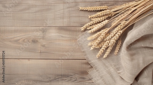 A flat lay image featuring a group of wheat sheaves arranged on a rustic brown wooden surface with a linen fabric photo