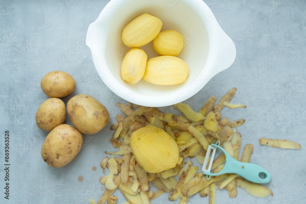 Peeled potatoes on the table and in the bowl.